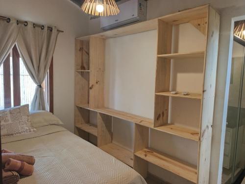 a bedroom with a bed with wooden shelves at Casa Xandó in Porto Seguro