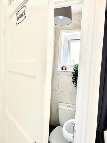 a bathroom with a white toilet and a window at Spacious 4-Bed Home Near Cambridge City Centre in CBG