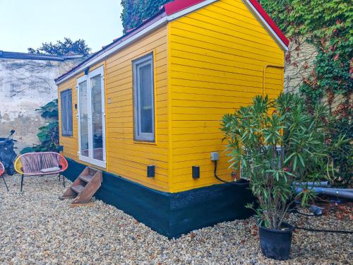 a yellow tiny house with a plant in front of it at Pura Vida Downtown Tiny houses in Bucharest
