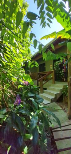 a porch of a house with stairs and flowers at Chalé Suítes Casa na Praia de Itamambuca in Ubatuba