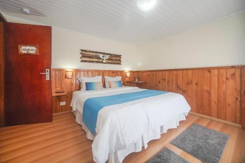 a bedroom with a large bed with wood paneling at Guida Residenza Pousada in Campos do Jordão