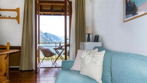 a living room with a blue couch and a balcony at Bellavista Riva in Riva di Solto