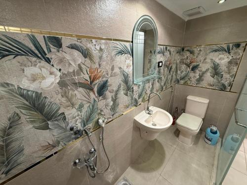 Un baño con inodoro, lavabo y espejo. en Cairo-Plaza, Manchester Hotel, en El Cairo