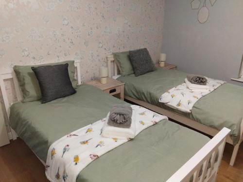 two twin beds in a room with green sheets at rosy in Totmonslow