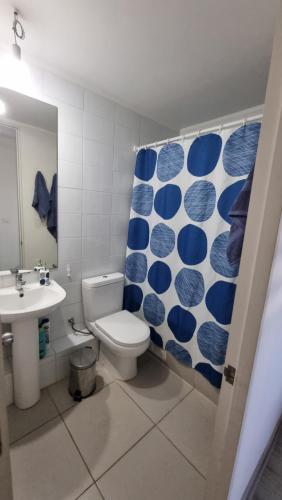La salle de bains est pourvue de toilettes et d'un rideau de douche bleu et blanc. dans l'établissement Departamento 2 dormitorios Temuco norte, à Temuco