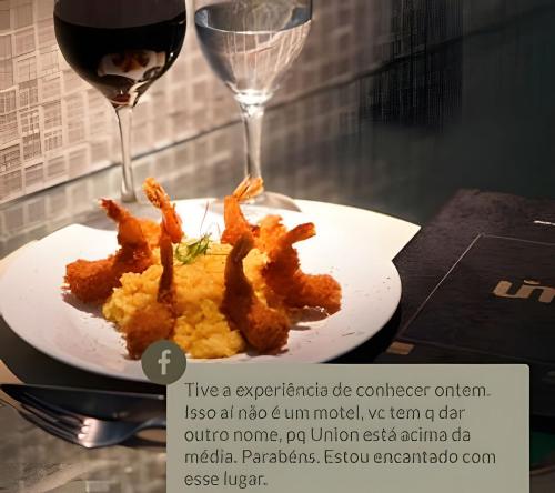 a plate of food next to a glass of wine at Union Motel (Adult Only) in Cabedelo