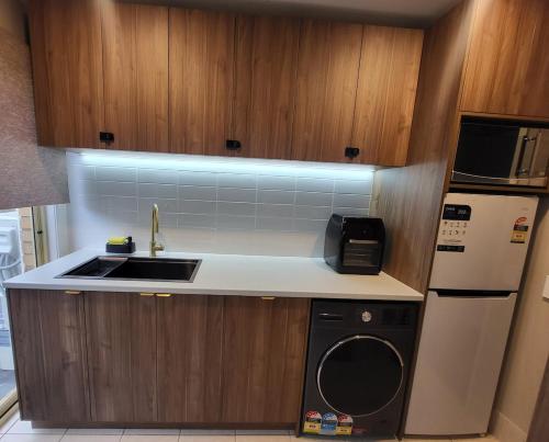 a small kitchen with a sink and a dishwasher at A Traveller's abode - Room 3 in Craigieburn