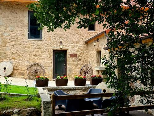a bench in front of a stone building with flower pots at Uíma River House