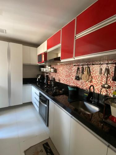 een keuken met rode kasten en een spoelbak bij Cop30 Apartmento in Belém
