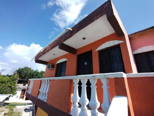 a orange house with a white railing on a balcony at Las Villas Champoton in Champotón
