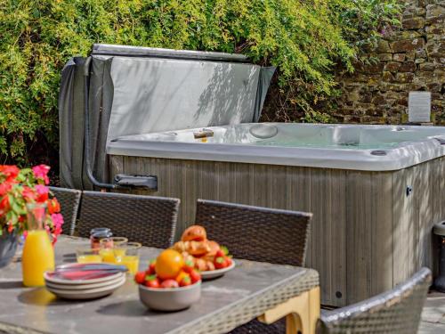 a table with a bowl of fruit next to a hot tub at 4 Bed in Bude SSHAM in Stratton