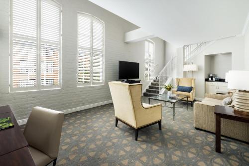 a living room with chairs and a couch and a television at Riverfront Hotel New Orleans in New Orleans