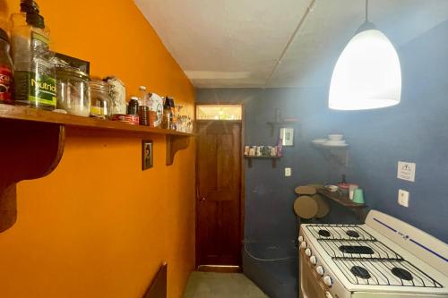 a kitchen with a stove and an orange wall at Isla Mujeres Punta Norte Private Bedroom 1 in Isla Mujeres