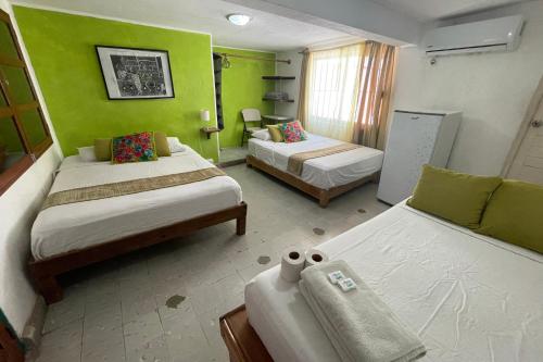 a room with two beds and a green wall at Isla Mujeres Punta Norte Private Bedroom 2 in Isla Mujeres