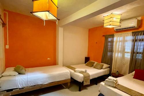 two beds in a room with orange walls at Family Retreat In Punta Norte Isla Mujeres in Isla Mujeres