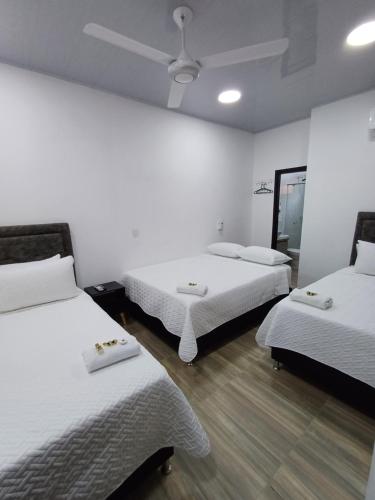 a room with two beds and a ceiling fan at Hotel Internacional Boutique Milan in Puerto Boyacá