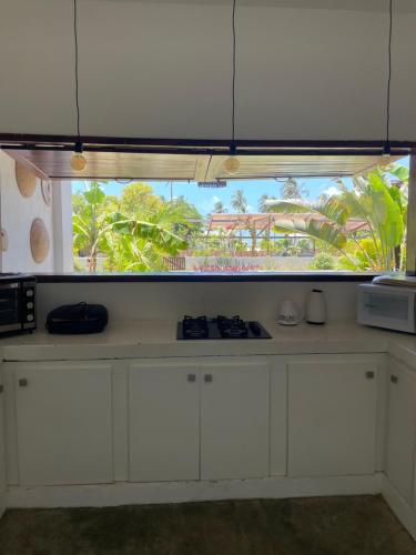 a kitchen with white cabinets and a large window at Casas Oceanicas in Icaraí