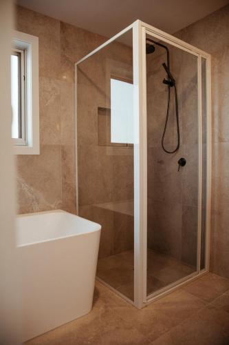 a bathroom with a shower with a tub and a sink at Sunnybank Sea & Stay in St Helens