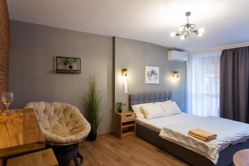 a bedroom with a bed and a chair and a table at Затишна студія біля метро Площа Конституції - Харківська набережна 3-10 in Kharkiv