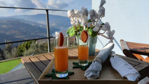a table with two glasses of juice and a vase of flowers at ArsDurium Douro hotel in Cinfães