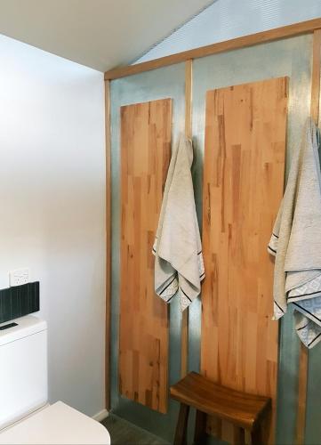 a bathroom with a toilet and towels hanging on a wall at D'entre Cabin in Woodbridge
