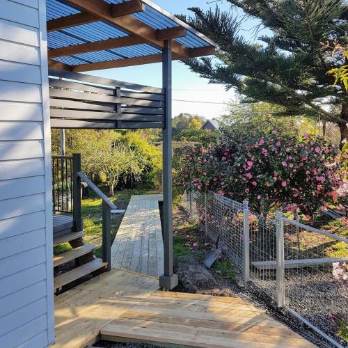 a wooden deck with a pergola and a fence at D'entre Cabin in Woodbridge