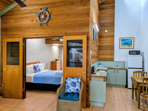 a bedroom with a bed and a kitchen with a table at Beachside Cottage - A Private Peaceful Hidden Gem 50m to Beach in Nelly Bay