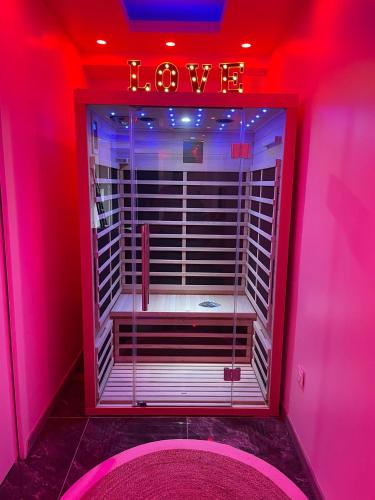 Una habitación rosa con un cartel que dice amor. en Appartement Love Room, jacuzzi spa & sauna, en Chevilly-Larue