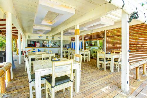 a restaurant with wooden tables and chairs on a wooden floor at LA PERLA STUDIOS with ROOFTOP POOL and SPA - PLAYA LOS CORALES in Punta Cana