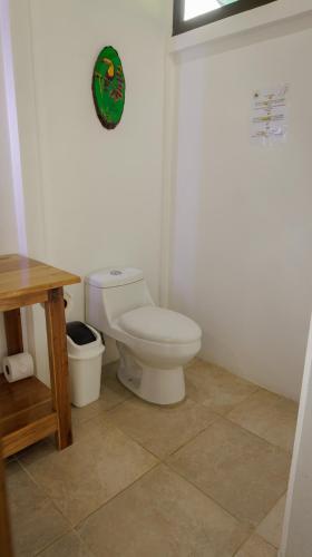 a bathroom with a toilet and a wooden table at Villa El Tucán in Bijagua