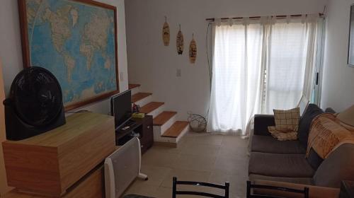 a living room with a couch and a television and a living room with stairs at Hostel Italia Fisherton in Rosario