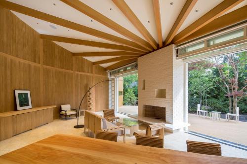 a living room with wooden walls and a large window at SHISHI-IWA HOUSE Karuizawa in Karuizawa