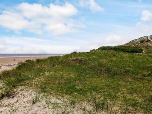 a grassy hill next to a beach with the ocean at 6 person holiday home in Fanø in Fanø