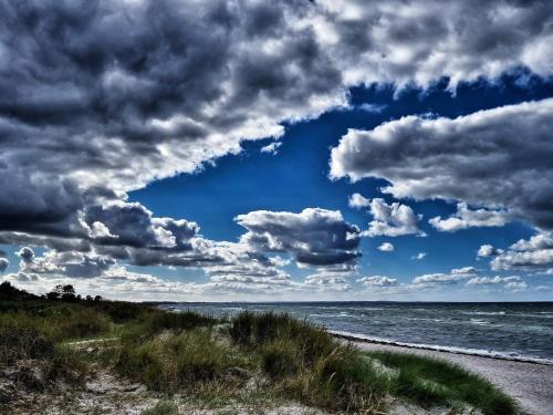 a beach with a cloudy sky and the ocean at 4 person holiday home in Glesborg in Glesborg
