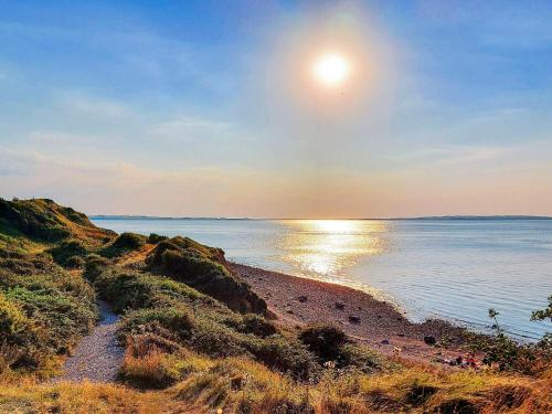 a beach with the sun setting over the water at 6 person holiday home in Løgstør-By Traum in Løgsted