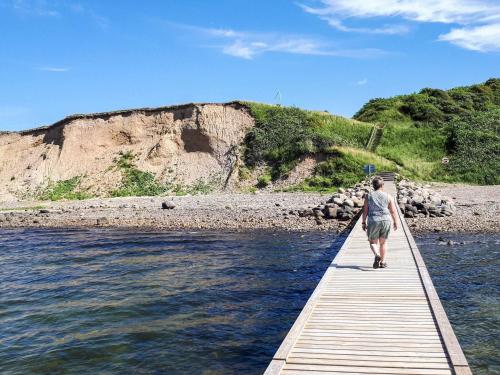 a person walking on a wooden bridge over the water at 6 person holiday home in Løgstør-By Traum in Løgsted