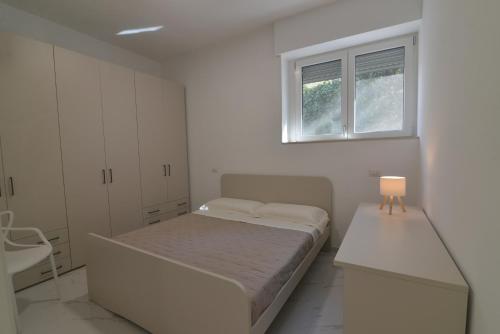 a white bedroom with a bed and a window at Central Apartment in Matera