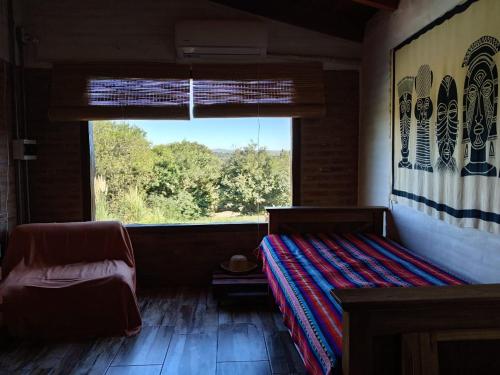 una habitación con una cama y una ventana grande en Cabaña Las liebres, en San Roque