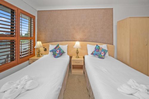 two beds in a room with two lamps at Country Plaza Motel Taree in Taree
