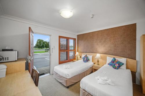 a hotel room with two beds and a television at Country Plaza Motel Taree in Taree