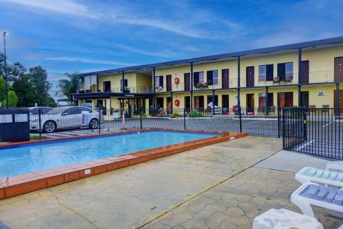 a building with a swimming pool in front of a building at Country Plaza Motel Taree in Taree