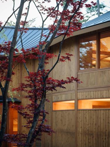 a tree with red leaves in front of a house at SHISHI-IWA HOUSE Karuizawa in Karuizawa