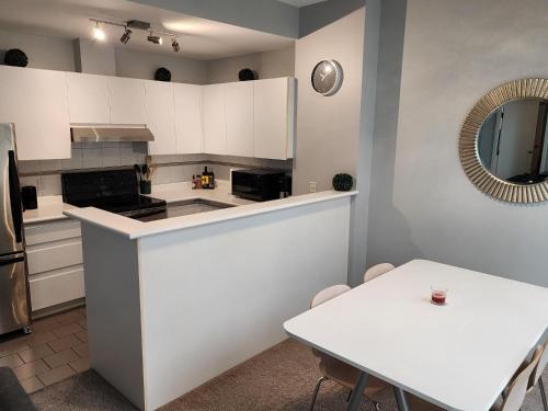 a kitchen with white cabinets and a table and a mirror at Cozy Condo in the heart of the city in Vancouver