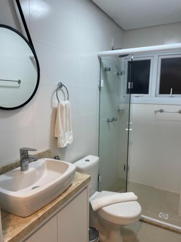 a bathroom with a sink and a toilet and a mirror at Apartamento Bolognese in Canela