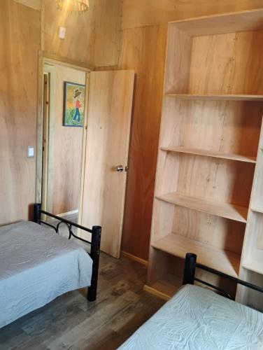 a bedroom with two beds and a book shelf at Cabaña para Desconectar in Barra de Portezuelo