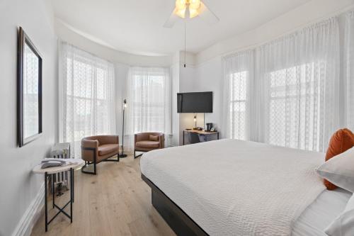 a white bedroom with a bed and a chair at The Andrews Hotel in San Francisco