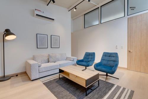 a living room with a couch and two blue chairs at Magusan Holiday Rentals in Cali