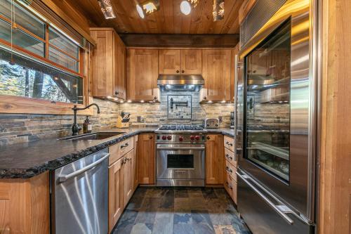 a kitchen with wooden cabinets and a stainless steel refrigerator at Classic Cabin in the Pines by Tahoe Getaways - Walk to Lake, Pet-Friendly 3 BR w Yard & Hot Tub! in Tahoe Pines