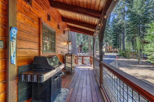 a porch with a grill on the side of a house at Classic Cabin in the Pines by Tahoe Getaways - Walk to Lake, Pet-Friendly 3 BR w Yard & Hot Tub! in Tahoe Pines