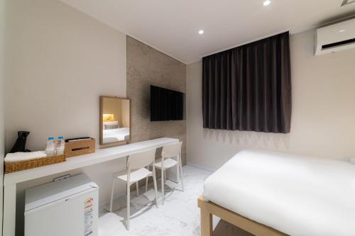 a room with a bed and a desk with chairs at The Central Hongdae in Seoul